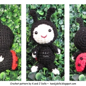 May include: Crocheted ladybug doll with a black body, red and black wings, and white face and feet. The doll has a smiling face and small antennae. The text "K & J Dolls" is visible on the doll's body. The background is green.