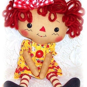 May include: A handmade rag doll with red yarn hair, a red and white gingham bow, and a yellow dress with a cherry print. The doll is wearing red and white striped stockings and black shoes.