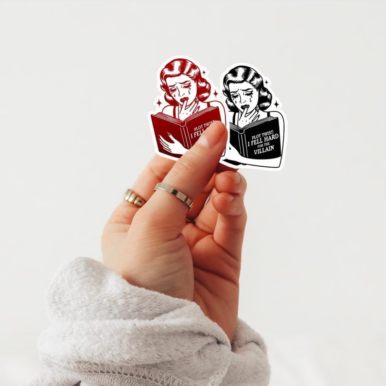 May include: Two stickers featuring a woman with tears in her eyes reading a book. The text on the book reads "Plot Twist I Fell Hard For The Villain". One sticker is red and the other is black and white.