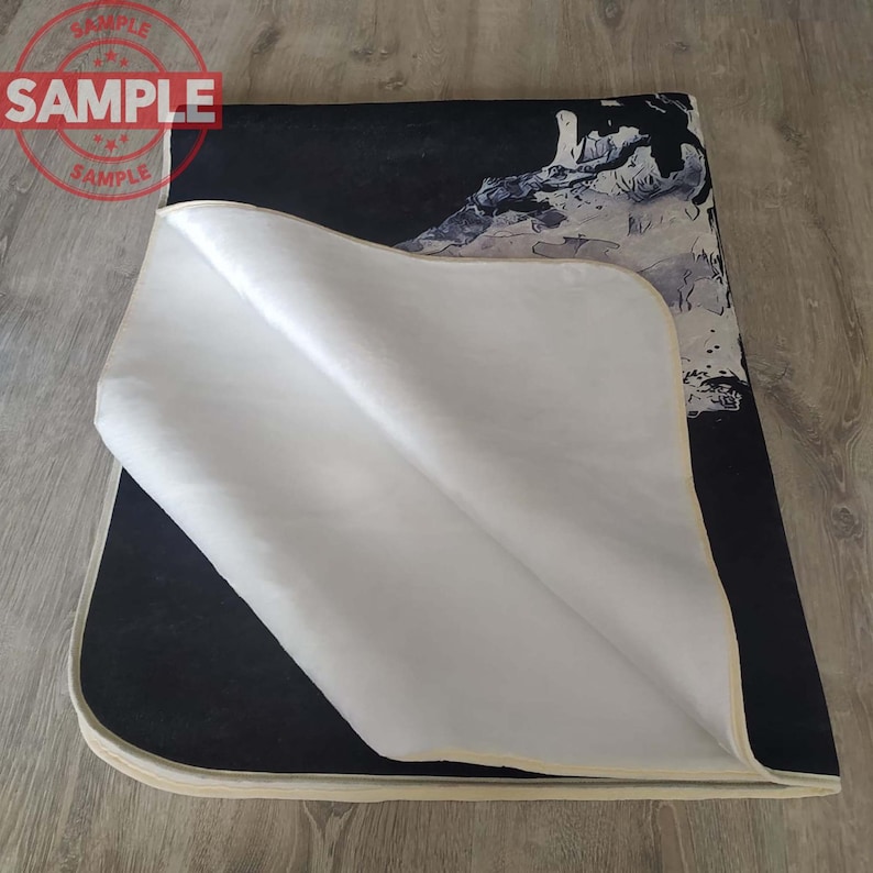 Puede incluir: Una alfombra de tela con un dise&ntilde;o abstracto en blanco y negro impreso sobre un fondo blanco. La alfombra tiene un borde de color crema.