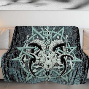 Op de afbeelding: Een teal en zwarte deken met een grafisch ontwerp van een geitenkop met hoorns, omringd door een pentagram en andere symbolen.