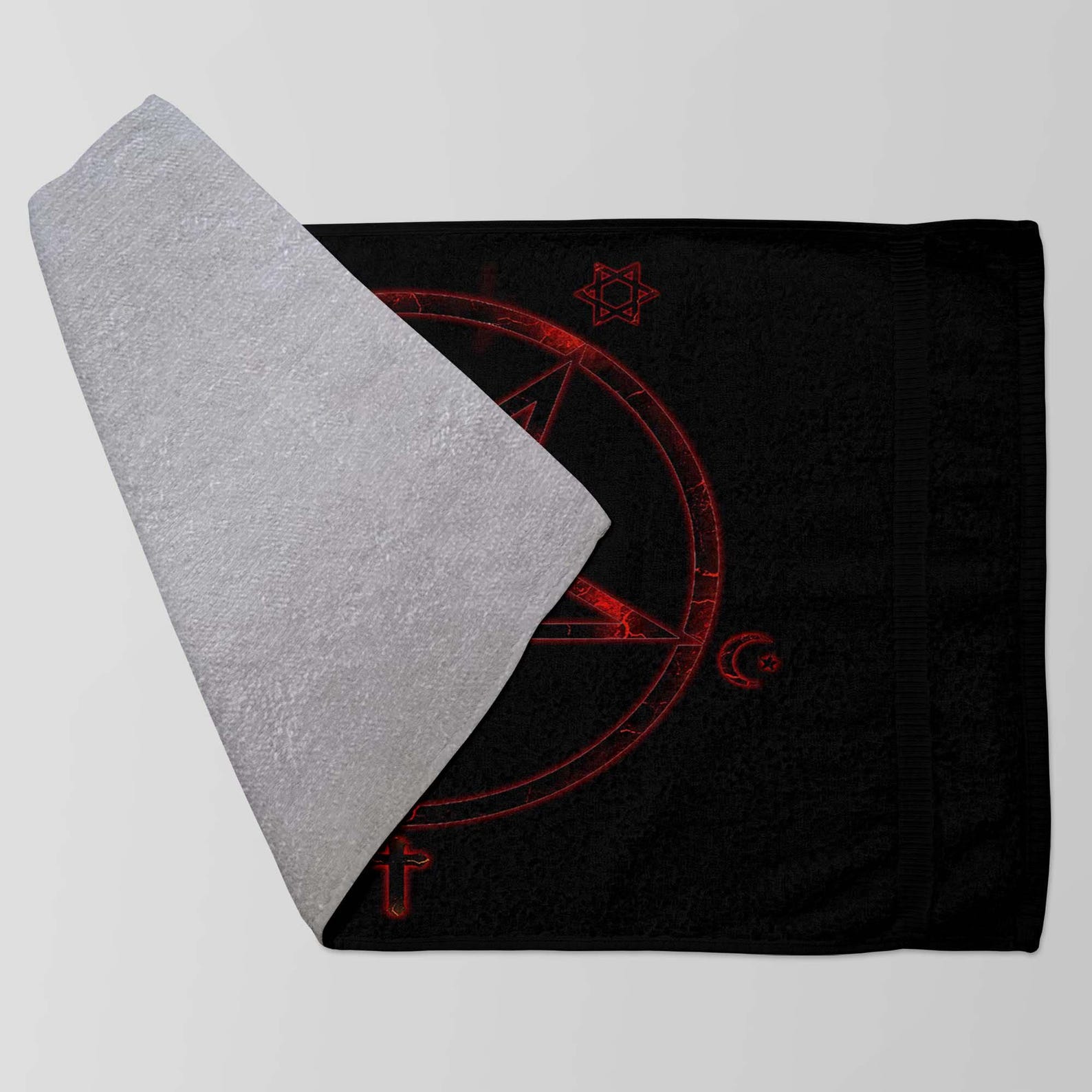 Folded black towel with red occult pentagram design, partially flipped to reveal soft white terry underside.