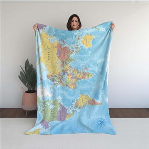 Può includere: Una coperta azzurra con una mappa del mondo dettagliata, raffigurante continenti e paesi. La coperta presenta una rosa dei venti nell'angolo in basso a destra. La mappa include i nomi dei paesi ed è realizzata in tessuto morbido e felpato.