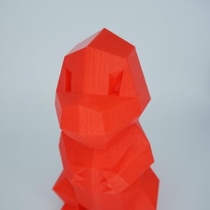 May include: A bright red, low-poly 3D printed figurine of a creature with a rounded head, two small eyes, and four legs.