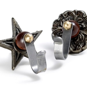 May include: Two decorative metal hooks with a star and a floral design. Each hook has a wooden knob with a brass accent.
