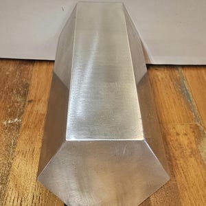 Pode incluir: Uma barra hexagonal de prata com acabamento escovado.