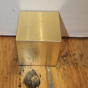 Pode incluir: Um cubo sólido de latão com acabamento escovado.