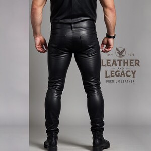 May include: A person wearing black leather pants. The pants are slim fitting and have a zipper fly. The person is standing with their back to the camera. The text "Leather and Legacy Premium Leather" is visible on the lower right side of the image.