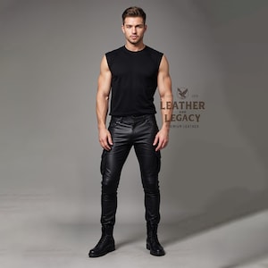 May include: A man wearing a black sleeveless shirt and black leather cargo trousers. The trousers have multiple pockets and a zip fly. The man is wearing black leather boots.
