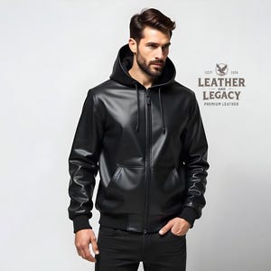 May include: A black leather jacket with a zipper closure and a hood. The jacket has a logo on the right side that says "Leather and Legacy Premium Leather".