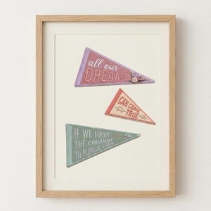 Könnte beinhalten: Ein gerahmtes Wandbild mit drei dreieckigen Wimpeln in gedecktem Rosa, Koralle und Salbeigrün. Die Wimpel zeigen den gestickten Text: all our DREAMS, CAN COME TRUE und IF WE HAVE THE courage TO PURSUE THEM, akzentuiert durch florale Motive und ein Schlüsselsymbol.