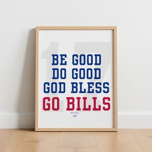 May include: Framed print with the text "BE GOOD DO GOOD GOD BLESS GO BILLS" in blue and red, with the number 17 in the background. The print is in a light wood frame.