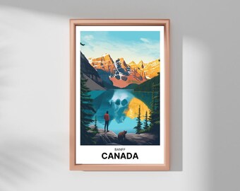 May include: A framed print of a mountain lake scene with a person and a bear standing on a rocky shore. The lake reflects the mountains and the sky. The text "BANFF CANADA" is printed at the bottom of the print.