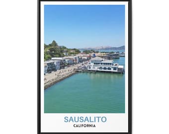 May include: A framed vertical wall art print featuring a scenic coastal view of Sausalito, California. The image displays a turquoise bay, a shoreline with buildings, and a clear blue sky. The text SAUSALITO CALIFORNIA is printed at the bottom.