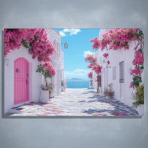 Puede incluir: Una vibrante impresión en lienzo representa una pintoresca escena de calle mediterránea. Los edificios blancos están adornados con buganvillas rosas, que conducen a una vista del mar y el cielo azules. Una puerta rosa añade un toque de color.