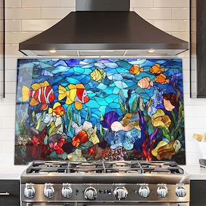 May include: A colorful kitchen backsplash featuring a stained glass design of an underwater scene. The artwork depicts various fish in shades of red, yellow, and orange swimming among coral and plants. The background is a mosaic of blue and turquoise.