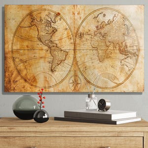 Op de afbeelding: Een vintage wereldkaart print met een sepia-tint, die de continenten in een ovale projectie weergeeft. De kaart bevat een kompasroos en wordt weergegeven op een houten oppervlak met decoratieve items.
