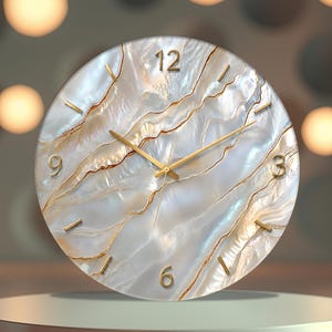 May include: A round wall clock featuring a pearlescent white and iridescent surface with wavy, gold-coloured veins. The clock face displays gold-coloured hour markers and numerals at the 12, 3, 6, and 9 positions, with thin gold-coloured hands.