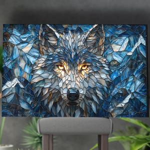 Puede incluir: Impresión en lienzo que presenta un retrato de lobo al estilo mosaico. La obra de arte muestra la cara de un lobo con penetrantes ojos amarillos, sobre un fondo de formas geométricas azules y blancas, que recuerdan montañas y paisajes helados. La paleta de colores es fría, con tonos azules, grises y blancos.