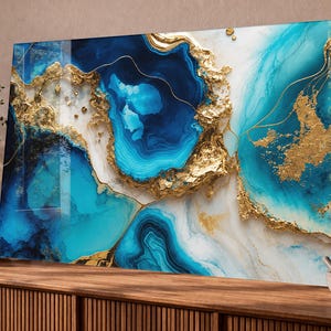 Könnte beinhalten: Ein rechteckiges Wandbild mit einem abstrakten, fließenden Design in wirbelnden Schattierungen von tiefem Marineblau, hellem Türkis und Weiß, akzentuiert durch texturierte, metallische Blattgoldadern, die eine geodenartige Optik erzeugen.