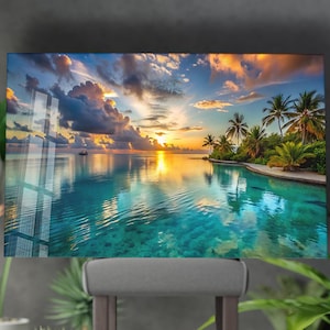 May include: A vibrant seascape print featuring a tropical sunset. The image showcases a calm, turquoise ocean reflecting the sky's colors, with palm trees on a small island. The sky is filled with clouds and the sun is setting.