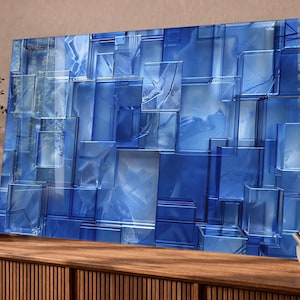 Puede incluir: Arte mural abstracto azul con un dise&ntilde;o geom&eacute;trico 3D. La obra de arte est&aacute; compuesta por formas rectangulares superpuestas en diferentes tonos de azul, creando un efecto texturizado y en capas. La pieza est&aacute; montada sobre una superficie de madera.