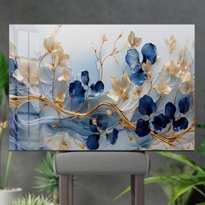 Könnte beinhalten: Ein rechteckiges Wandkunstwerk mit floralem Design. Es zeigt blaue und cremefarbene Blumen mit goldenen Stielen und Akzenten vor einem blau-weißen Hintergrund. Das Kunstwerk ist an der Wand befestigt und schafft ein dekoratives Element.