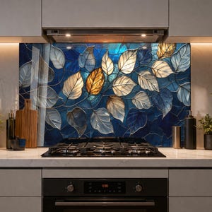 May include: A kitchen splashback featuring a stained glass design of overlapping leaves in shades of deep blue, white, and gold. The leaves have visible vein details and are arranged against a dark blue background, installed behind a gas stove.