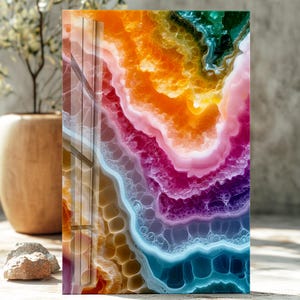 Puede incluir: Una obra de arte rectangular y abstracta con un acabado brillante. La obra presenta un diseño vibrante y en capas con colores que van del azul profundo al naranja y al verde. La pieza se asemeja a una sección transversal de una geoda o piedra de ágata.