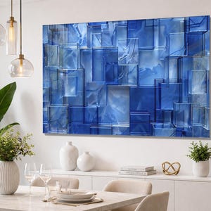 Puede incluir: Arte mural abstracto azul con un dise&ntilde;o geom&eacute;trico 3D de formas rectangulares superpuestas. La obra de arte tiene un acabado brillante y est&aacute; montada en una pared blanca. La habitaci&oacute;n est&aacute; decorada con muebles y decoraci&oacute;n modernos.