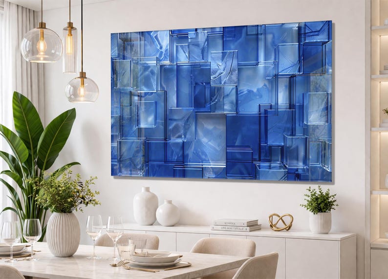 Puede incluir: Arte mural abstracto azul con un dise&ntilde;o geom&eacute;trico 3D de formas rectangulares superpuestas. La obra de arte tiene un acabado brillante y est&aacute; montada en una pared blanca. La habitaci&oacute;n est&aacute; decorada con muebles y decoraci&oacute;n modernos.