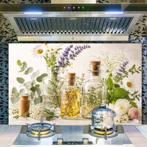 May include: A kitchen splashback panel featuring a printed design of three clear glass bottles filled with herbs and flowers, including daisies, lavender, and eucalyptus, alongside a small wooden container and a silver pot on a stove.