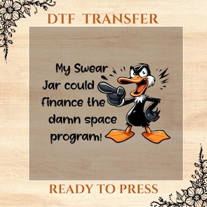 May include: A brown and black cartoon duck with an angry expression points to the text "My Swear Jar could finance the damn space program!" on a brown background. The text "DTF TRANSFER" is at the top of the image and "READY TO PRESS" is at the bottom.
