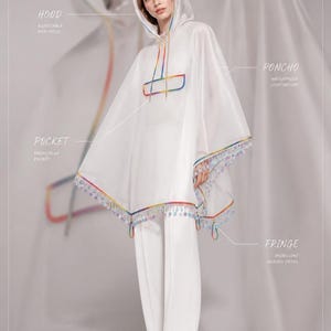 May include: A translucent white hooded poncho featuring a rainbow-colored trim, a front flap pocket, and an iridescent beaded fringe along the hem. The garment includes labels identifying the hood, poncho, pocket, and fringe details.