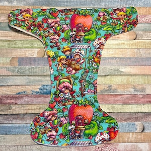 May include: A cloth diaper with a colorful pattern featuring cartoon characters, strawberries, and apples on a teal background. The diaper has a white interior and is designed for babies. The overall theme is a whimsical, playful design.