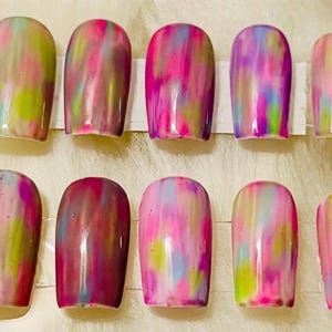 Può includere: Dieci unghie finte con un design astratto colorato. Le unghie sono dipinte con una miscela di rosa, viola, verde e giallo.