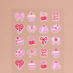 Puede incluir: Una hoja de pegatinas rosas y rojas con varios diseños, incluyendo lazos, cerezas, cupcakes, corazones y donuts. Las pegatinas están sobre un fondo transparente y tienen un acabado brillante.