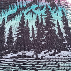 May include: A black and blue crocheted throw blanket with a pattern of trees and a starry sky. The blanket has a fringed edge.