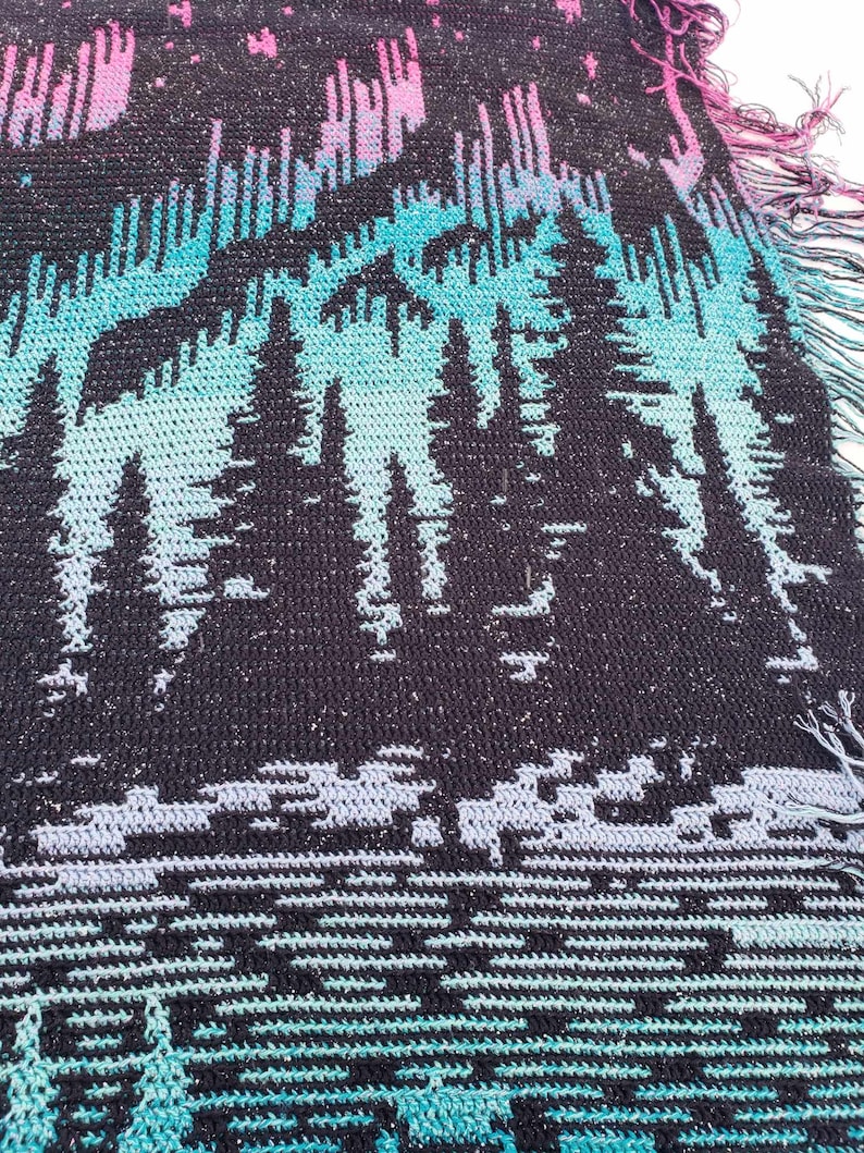 May include: A black and blue crocheted throw blanket with a pattern of trees and a starry sky. The blanket has a fringed edge.
