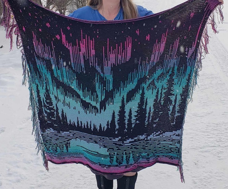 May include: A crocheted blanket with a black background and a colorful aurora borealis design. The blanket has fringe on all sides.