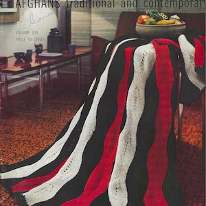 May include: A vintage magazine cover titled "Spinnerin" featuring a black, red, and white striped afghan. The cover text reads "AFGHANS traditional and contemporary". A bowl of fruit sits on a table in the background.