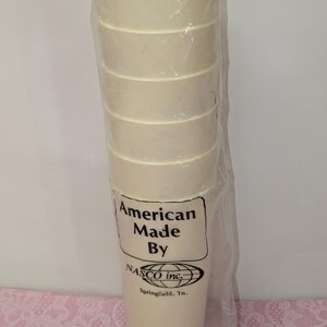 May include: A stack of six off-white, cylindrical cups wrapped in clear plastic. The cups have a ridged design. The packaging includes the text "American Made By NASCO inc. Springfield, Tn."