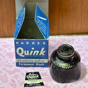 May include: Vintage Parker Quink ink bottle and box. The box is blue and white with the word "Quink" in large letters. The ink bottle is dark glass with a metal lid. A small label is also present.