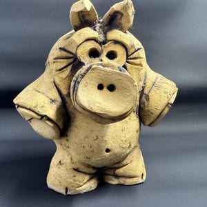 Peut inclure: Figurine en céramique de couleur beige représentant une créature de dessin animé avec de grands yeux, un museau proéminent et de petites oreilles. La figurine a les bras sur les côtés et un petit nombril. Design fantaisiste et artisanal.