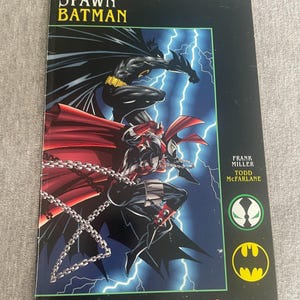 May include: A comic book titled "Spawn Batman" with illustrations of Batman and Spawn. The cover art shows the characters in action against a backdrop of lightning. The Image Comics logo is at the bottom.