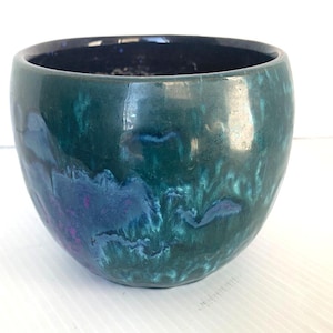 May include: A round ceramic planter with a green glaze and blue and purple marbling. The planter has a dark blue rim.