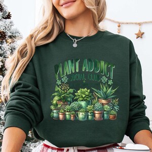 a woman wearing a green sweatshirt with plants on it