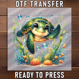 May include: DTF TRANSFER and READY TO PRESS text on a square image. The image features a cartoon sea turtle with a green shell and big eyes, swimming among aquatic plants and bubbles. The background is a light gray with a wood grain pattern.