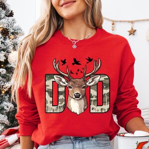 a woman wearing a red sweatshirt with a deer on it