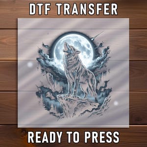 May include: A DTF transfer sheet featuring a graphic illustration of a wolf howling at a large full moon. The design includes dark blue and grey tones, clouds, a rocky cliff, and a shooting star. The text DTF TRANSFER and READY TO PRESS is visible.
